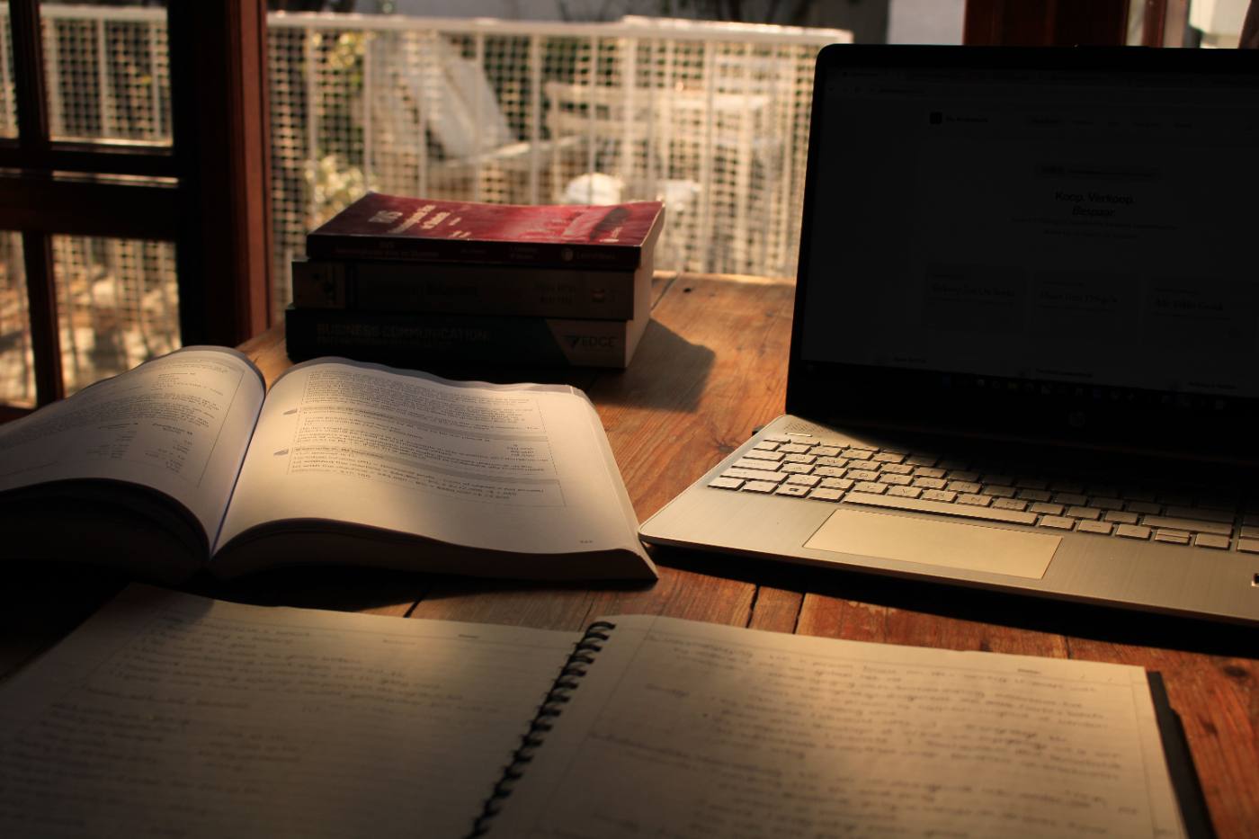 Handboeke, notas en 'n skootrekenaar op 'n tafel